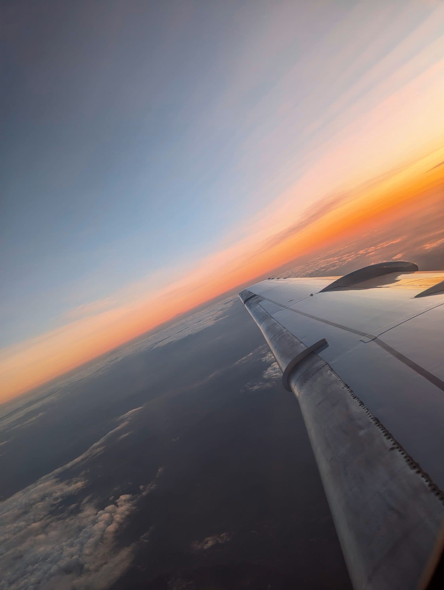 An aircraft wing over a sunset horizon